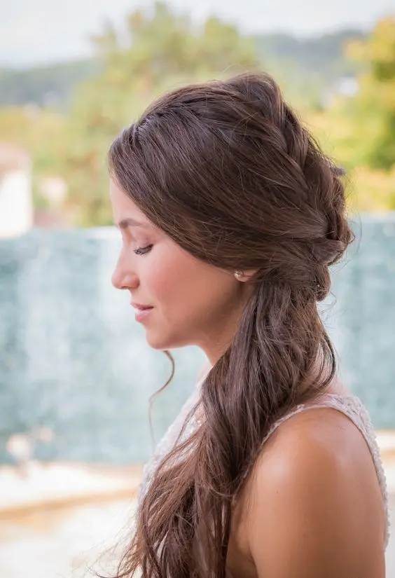 a messy textural sie half updo with a braid and messy hair down is a cool idea for a casual wedding