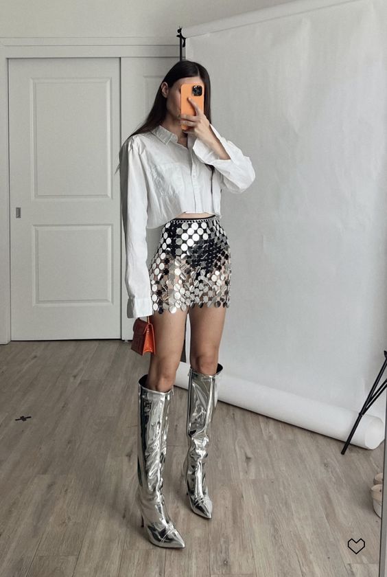 a party look with a cropped button down, a silver sequin mini, silver boots and a small red bag is amazing