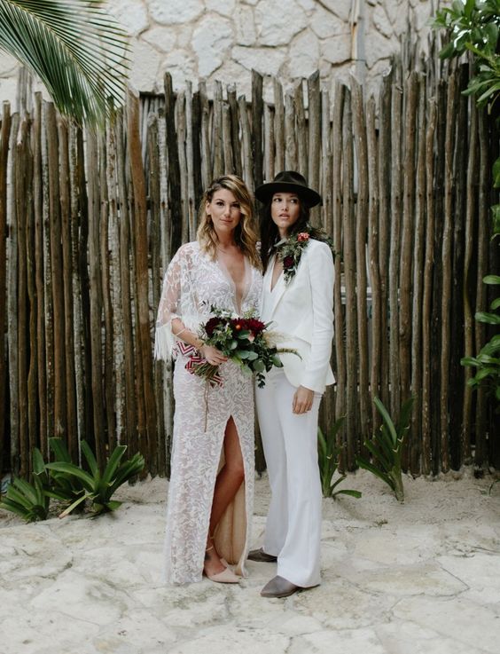 a white pantsuit with flare pants, grey boots, a black hat, a romantic boho lace wedding dress with a plunging neckline, a front slit and fringe on the sleeves