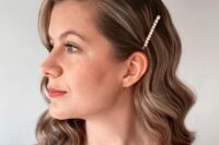 medium wavy hair can be styled side-swept, with a side part and a pearl hair pin is a cool solution for a modern bride