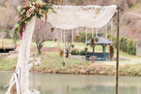 06 The wedding arch was made of wood and decorated with wwhite tulle, giant pinecones and lush holiday florals