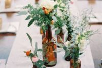 10 brown bottles coupled with bright green and white flowers create a chic and style-worthy display for the outdoor, spring table
