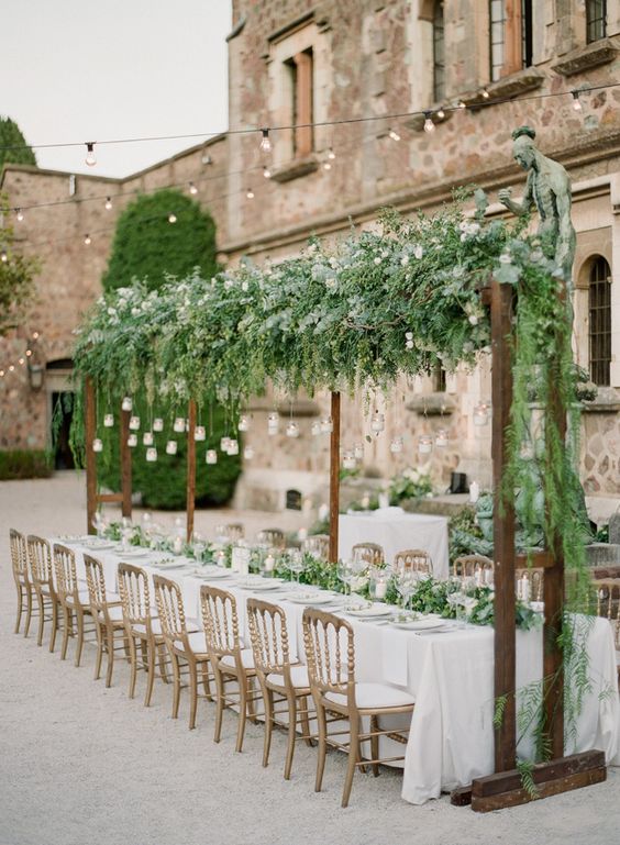 a greenery table runner echoes with a lush greenery arch over the table