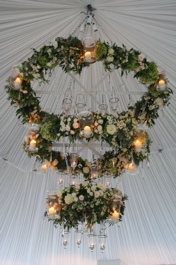 a trio of floral chandeliers with greenery and candle holders