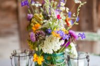 18 blue jars with wildflowers and candle holders for a centerpiece