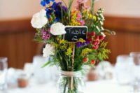 19 bold wildflower centerpiece with a chalkboard table number on a wood slice