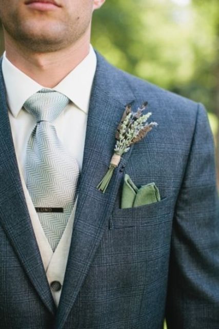dark grey suit, a neutral vest and shirt, a green boutonniere