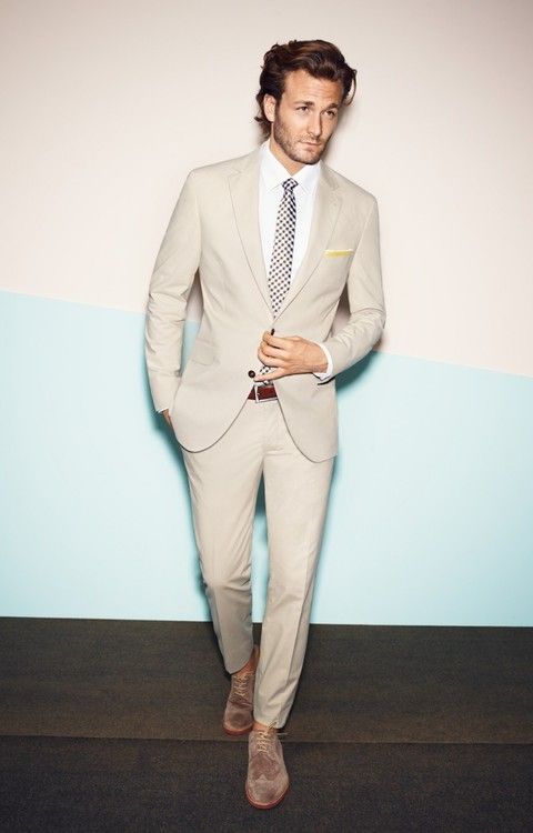 cream colored suit with a polka dot tie and light brown suede boots