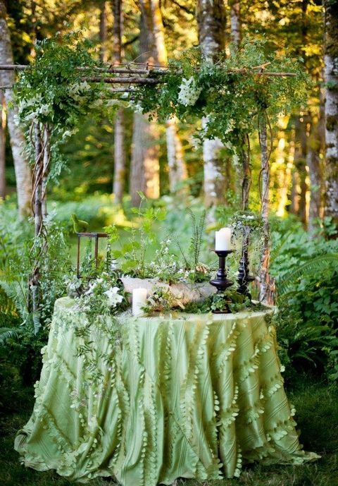 green tablecloth, a greenery arch and potted greenery on the table are ideal for displaying a woodland cake