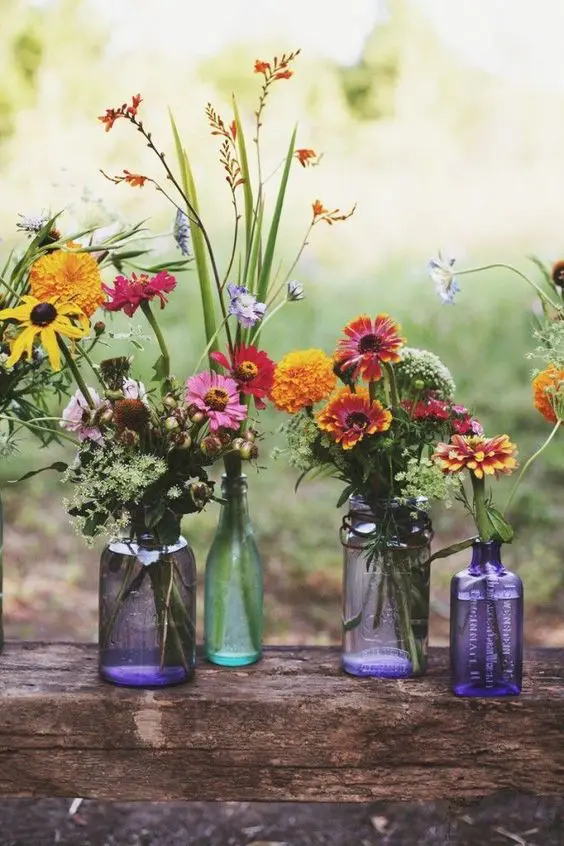 vibrant wildflowers in purple vases and bottles