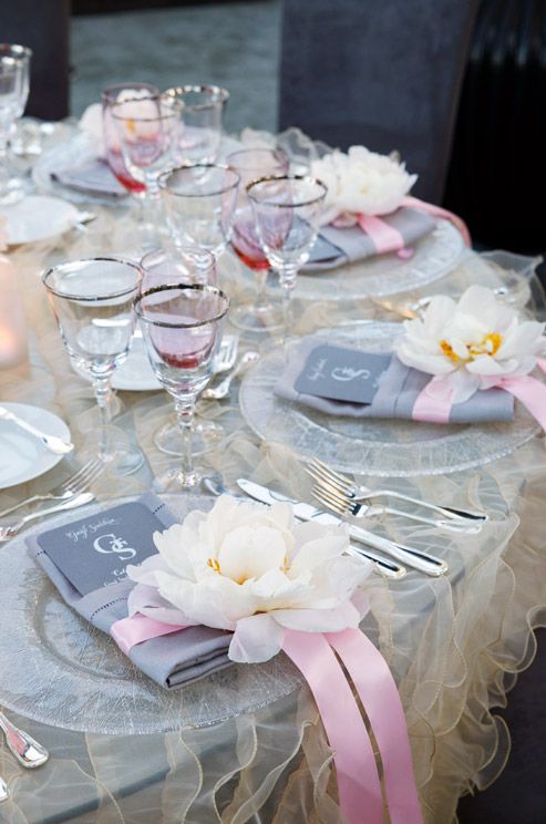 light grey tablescape with a ruffled tablecloth and pink glasses and ribbon