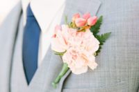 32 light grey suit with a vest, a navy tie and a peach-colored flower boutonniere