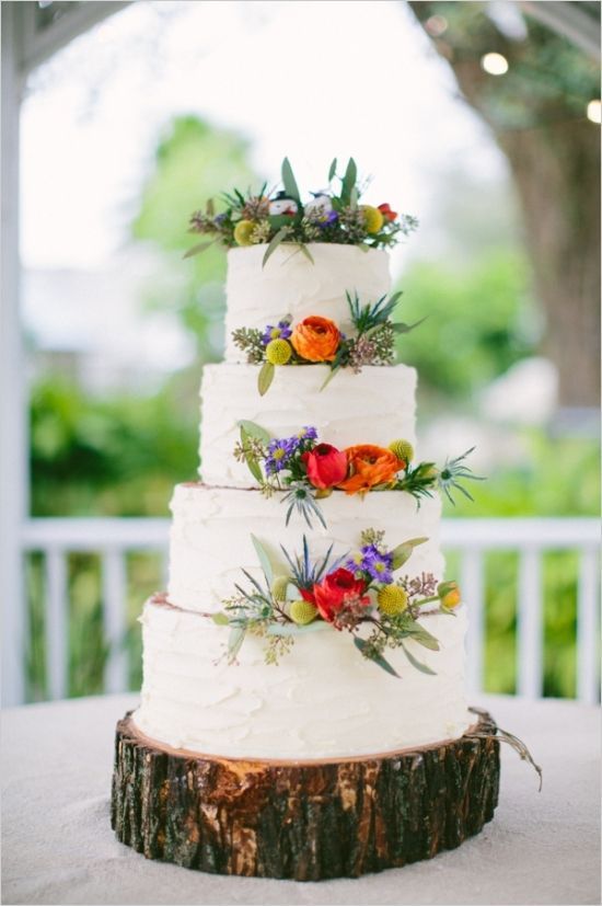 beautiful white wedding cake with floral decor displayed on a wooden slice