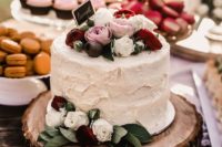 41 rustic buttercream wedding cake with pink, red and white roses on a wood round