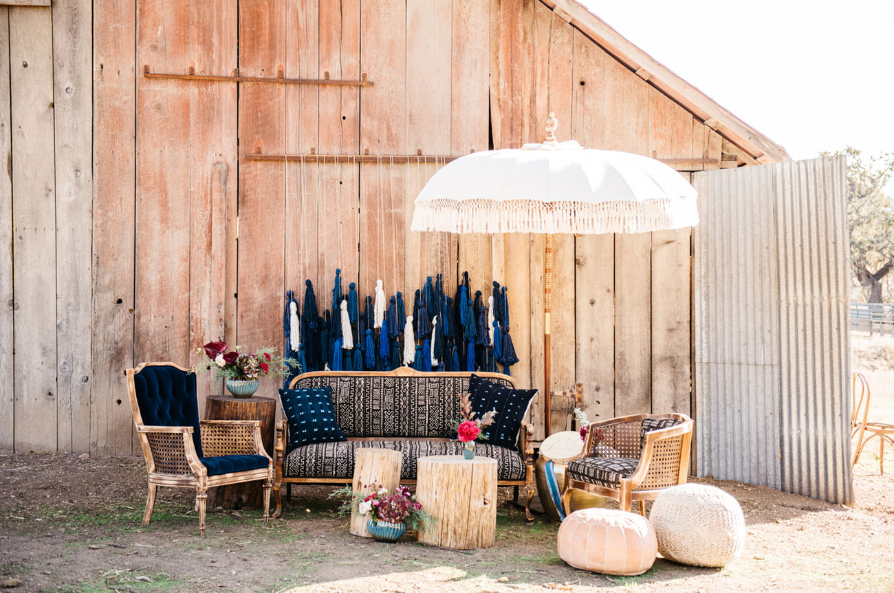 Look at this outdoor lounge zone with oversized tassel backdrop and boho touches, it's amazing