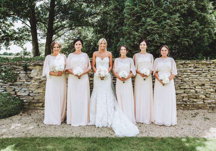 The bride chose a paghetti strap wedding dress with a cathedral length veil and her bridesmaids were wearign neutral-colored dresses