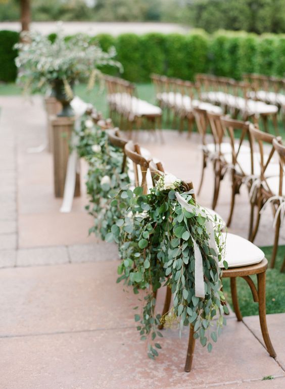 aisle chairs decorated with eucalyptus and ribbons