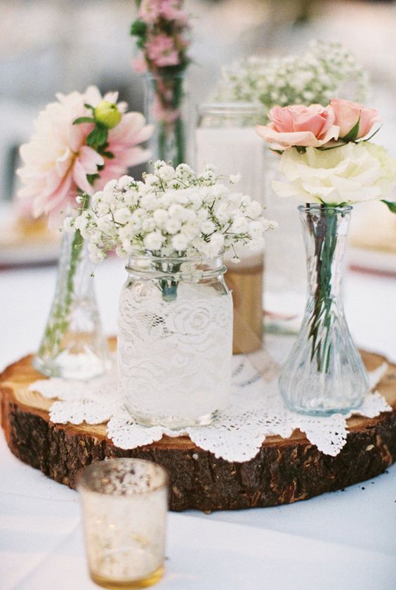 wood slice with doilies, mason jars and bottles with flowers