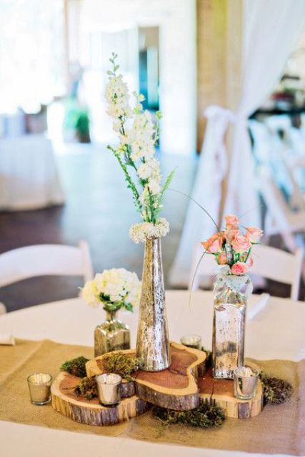 eye catchy centerpiece with several wood slices and mercury vases
