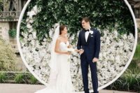 19 circular backdrop adorned with greenery and white hued bloom which will set a modern and elegant wedding statement