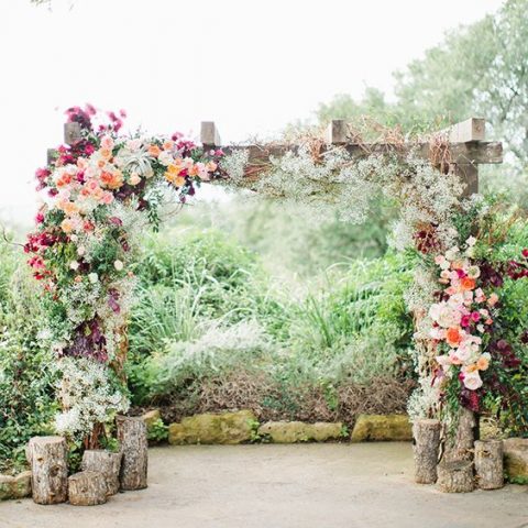 vibrant, lush floral arch with ranunculus, anemones, stock blooms and green jasmine vine