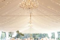 25 neutral wedding tent with a lot of lights and chandeliers