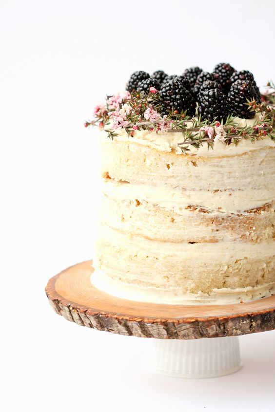 wood slice cake stand with a cup, a naked wedding cake with blackberries