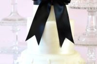 32 chic white cake with a ruffle tier and a large black bow