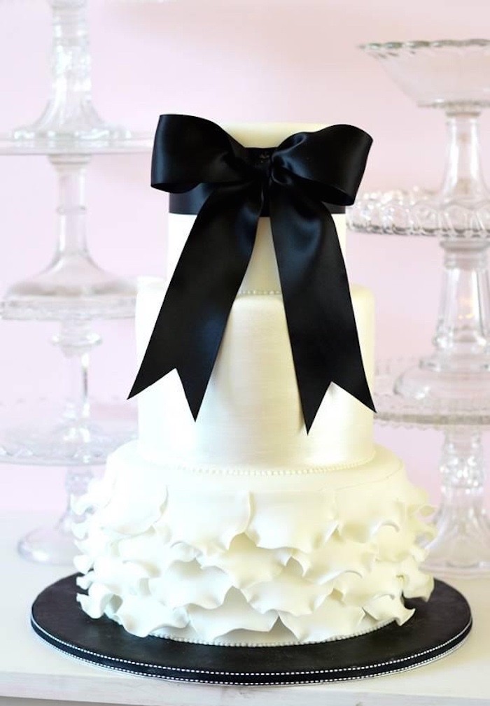 Chic white cake with a ruffle tier and a large black bow