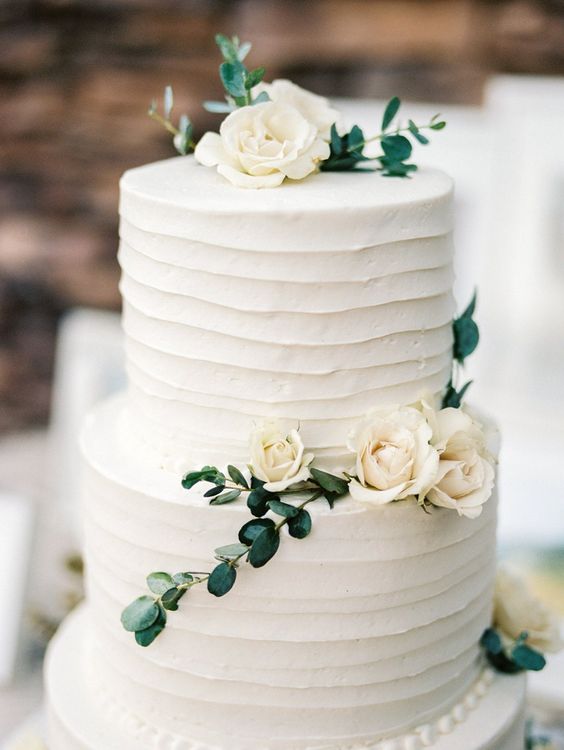 simple white cake decorated with greenery and neutral flowers