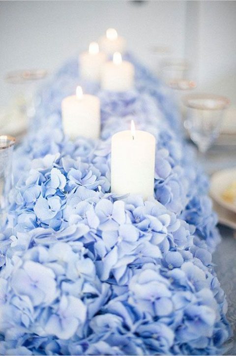 pale blue hydrangeas create a lush bed for placing a row of candles