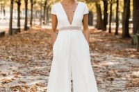 a chic modern white jumpsuit with wideleg pants and pockets, a plunging neckline, short sleeves and silver shoes