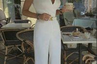a chic white jumpsuit with wide straps and a V-neckline, hot red shoes, jewelry and a hat
