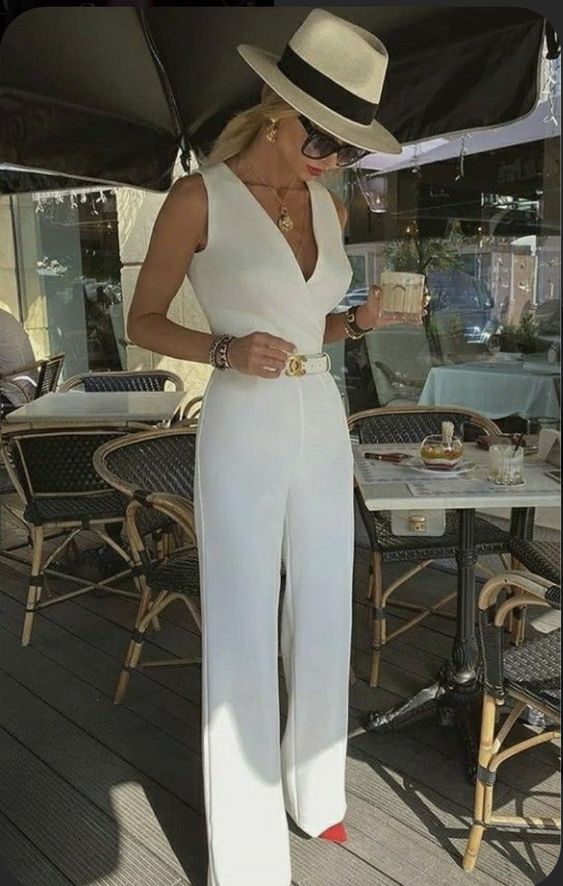a chic white jumpsuit with wide straps and a V-neckline, hot red shoes, jewelry and a hat