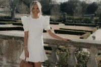 a white mini dress with a high neckline, puff sleeves and a ruffle edge, nude shoes and a brown bag for a bridal shower
