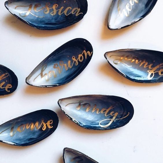 blue oyster shells with gold calligraphy as escort cards and favors in one