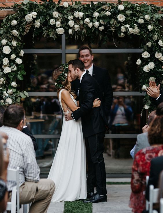 greenery and white roses wedding arch will make everyone forget that it's an urban location