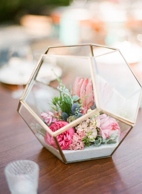 a terrarium filled with flowers and sand for a cool centerpiece