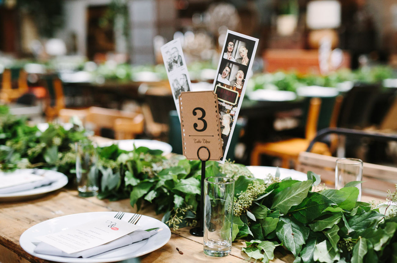 Greenery garlands were used instead of centerpieces, and photos of the couple for table numbers