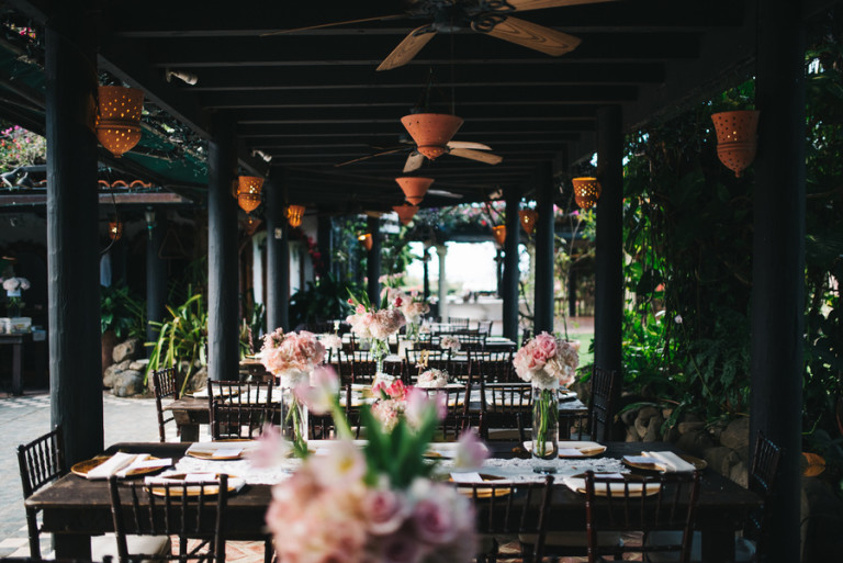 Simple outdoor reception with blush florals and fans over all the tables for more comfort