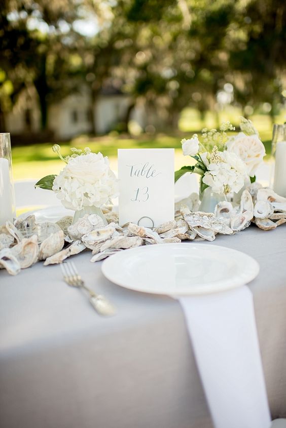 an oyster shell garland with white flowers are great for decorating a beach wedding table