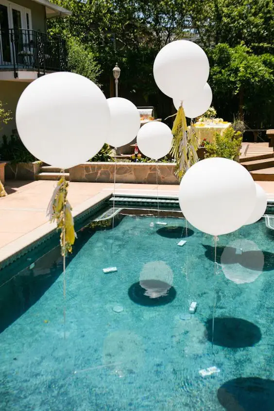 giant white balloons decorated with tassels over the pool