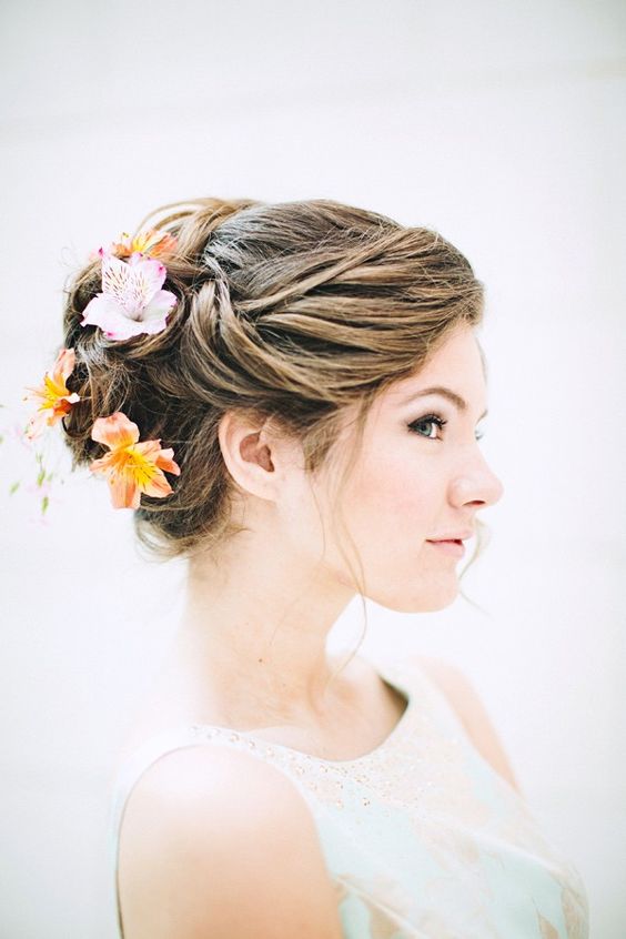 elegant wedding updo with tropical blooms in it