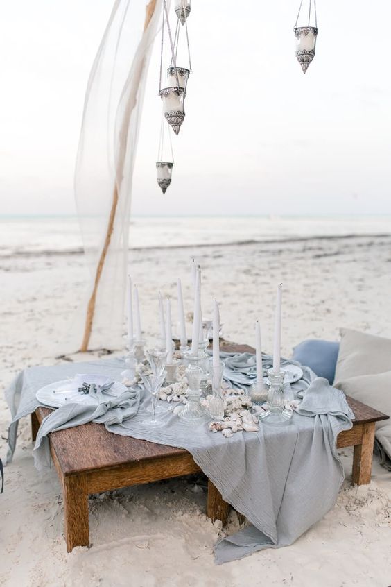 beach wedding picnic table with a light blue tablecloth, shells and candles