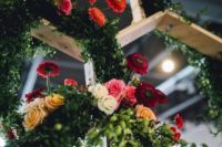 22 multicolored flowers hanging from wooden honeycomb structures above tables