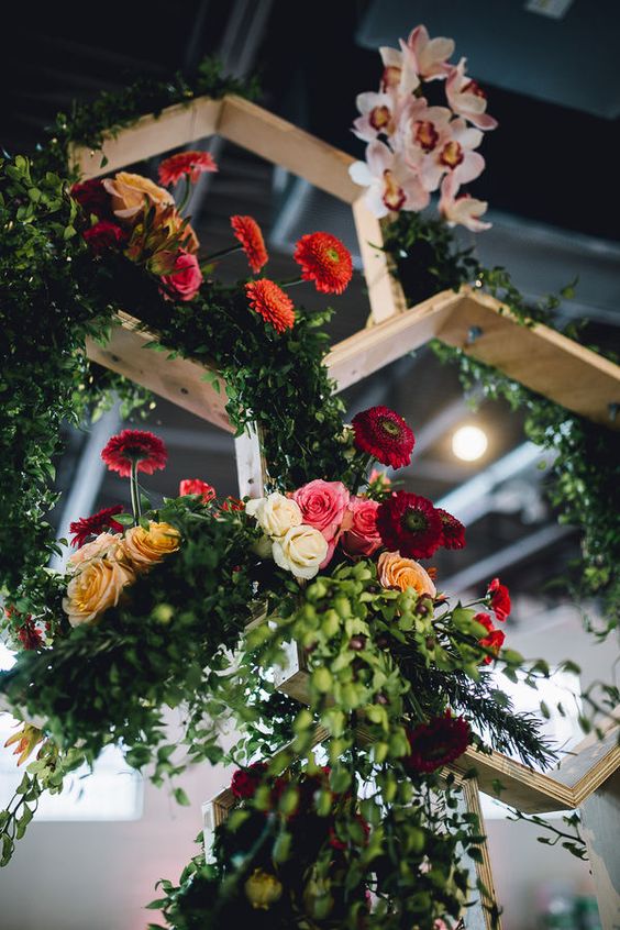 multicolored flowers hanging from wooden honeycomb structures above tables