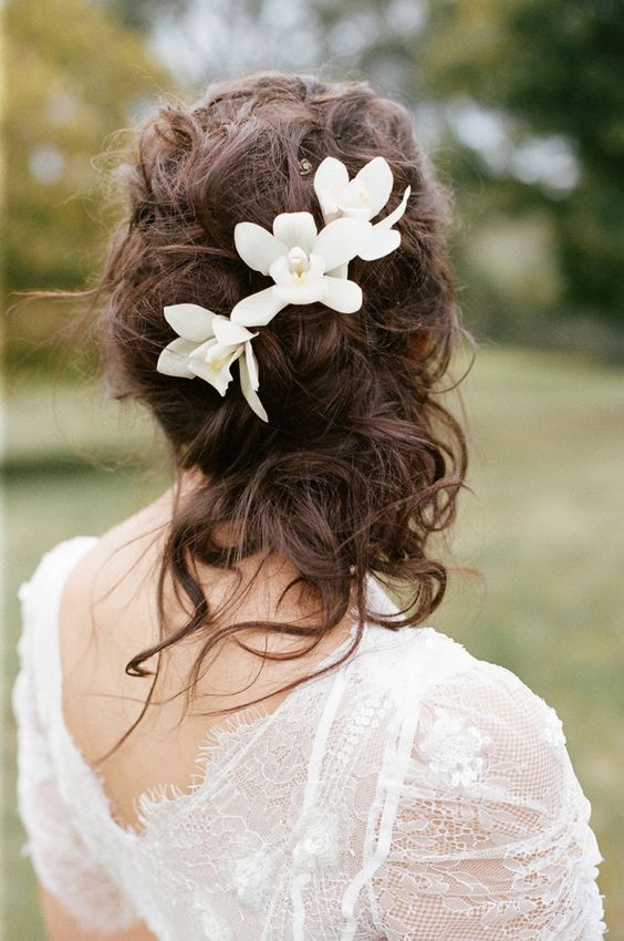 messy curly wedding half updo with tropical flowers
