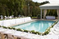 34 poolside reception table decorated with a greenery and white rose table garland