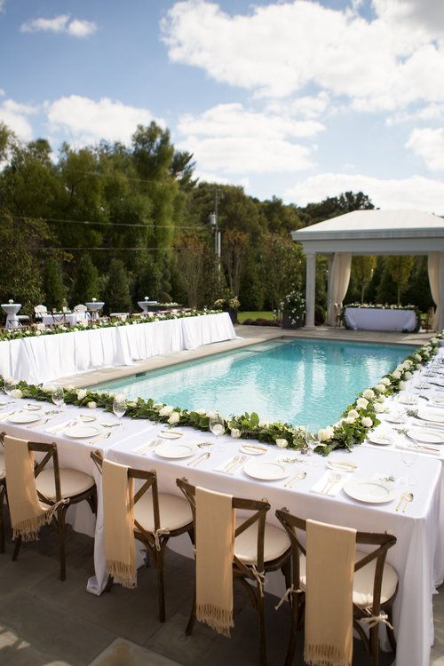 poolside reception table decorated with a greenery and white rose table garland