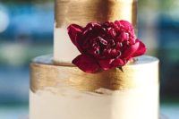 34 white cake decorated with gold leaf with a bold bloom